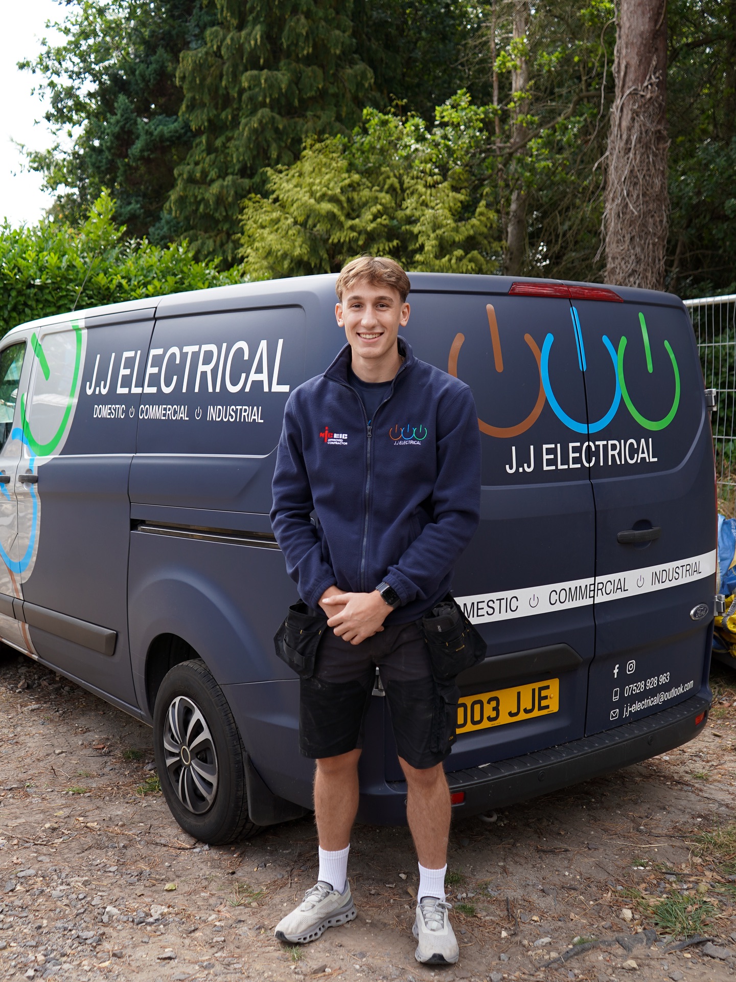 Young electrician standing next to branded JJ Electrical van — a typical sole trader who'll be affected by MTD